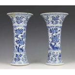 China, paar blauw-wit porseleinen stelvazen, Kangxi, met fijn decor van bloesem in vakwerk (één