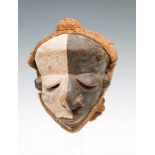 DRC., Pende, sickness mask with slanting eyes, miss formed bulbous nose and mouth, painted in two