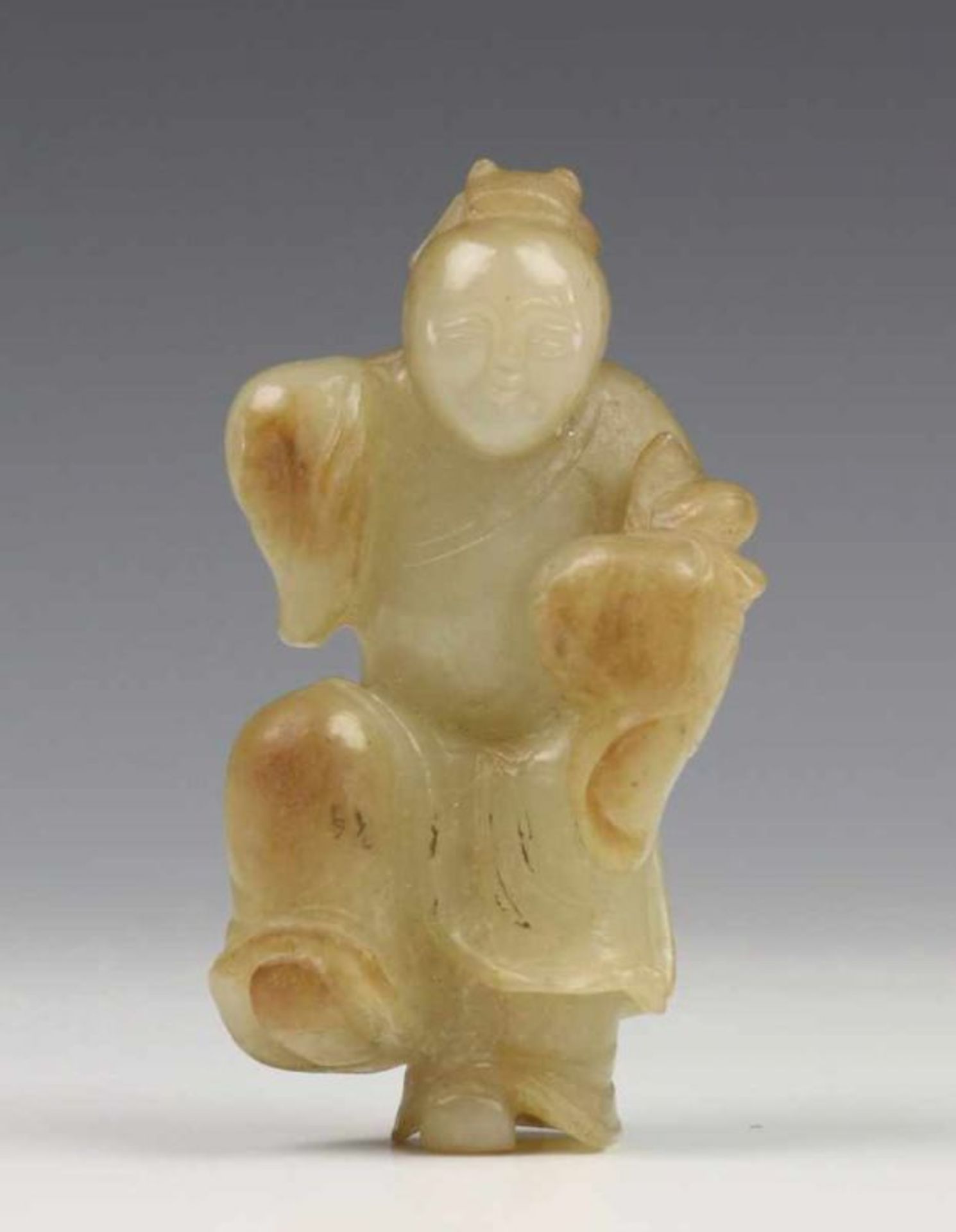 China, celadonkleurig jade snijwerk, 19e eeuw; Zotje met perzik in de hand en opgetrokken been l.