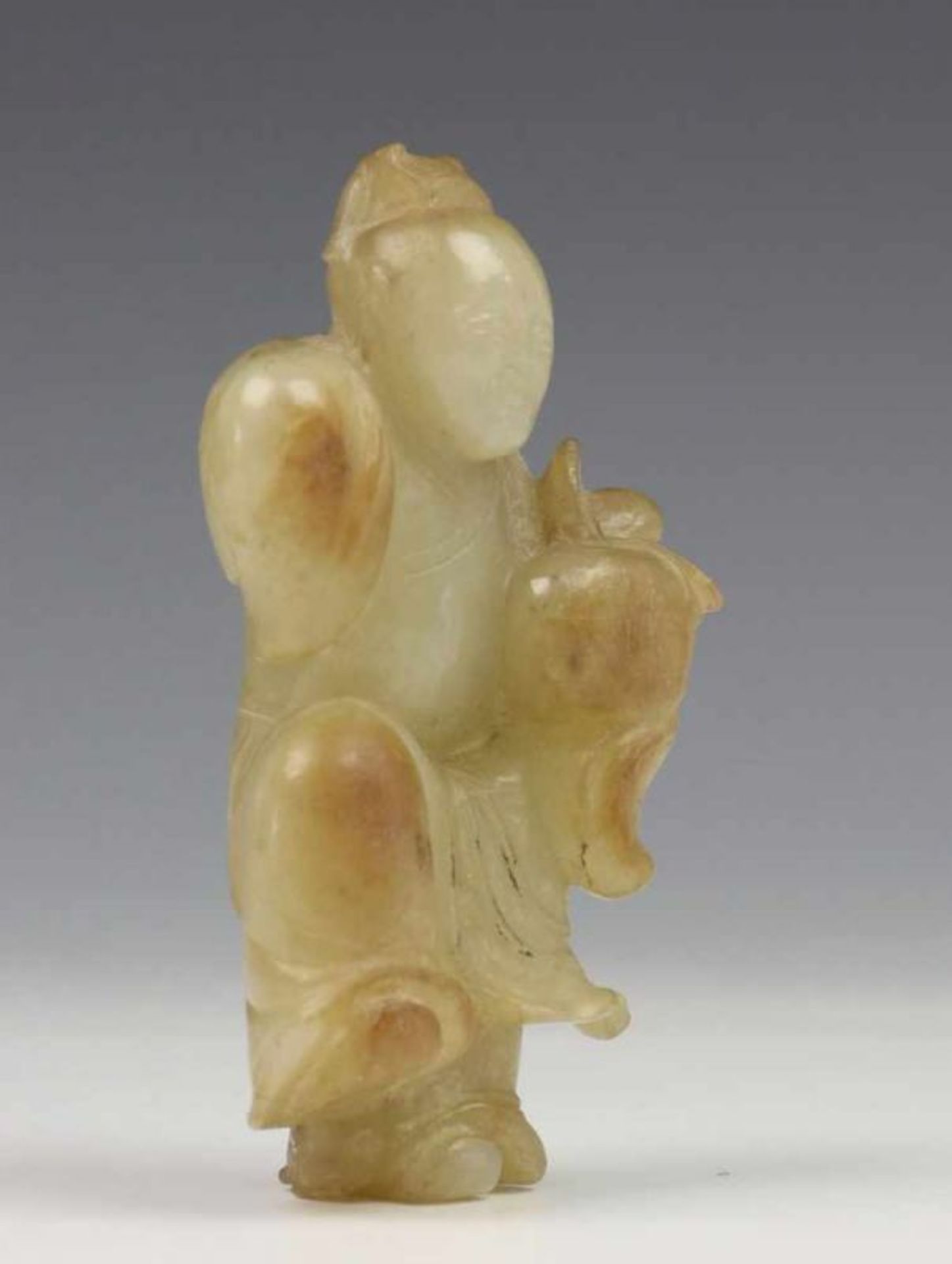 China, celadonkleurig jade snijwerk, 19e eeuw; Zotje met perzik in de hand en opgetrokken been l. - Image 2 of 2