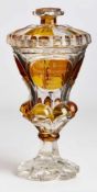 Deckelpokal, Böhmen um 1850. Farbloses Glas, partiell bernsteinfarben lasiert. Kon. Kuppa m. breiten
