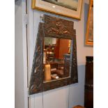 An Arts and Crafts embossed and beaten copper framed mirror