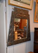 An Arts and Crafts embossed and beaten copper framed mirror