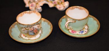 A pair of Meissen coffee cups and saucers painted with figures and flowers.
