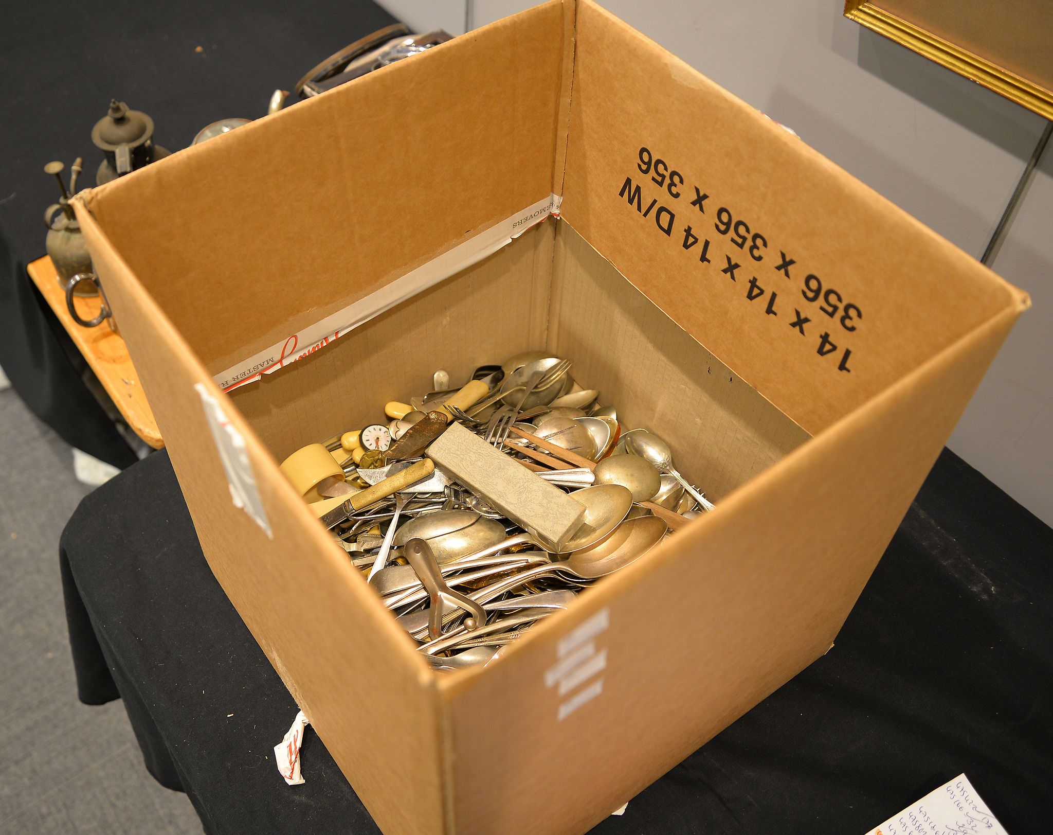 A box containing a mixed selection of silver-plated items, mostly flatware