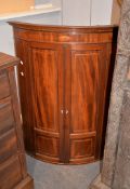 A George III mahogany and inlaid hanging corner cupboard, of bowfront outline