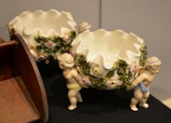 A pair of Sitzendorf flower-encrusted tripod baskets with putti supports