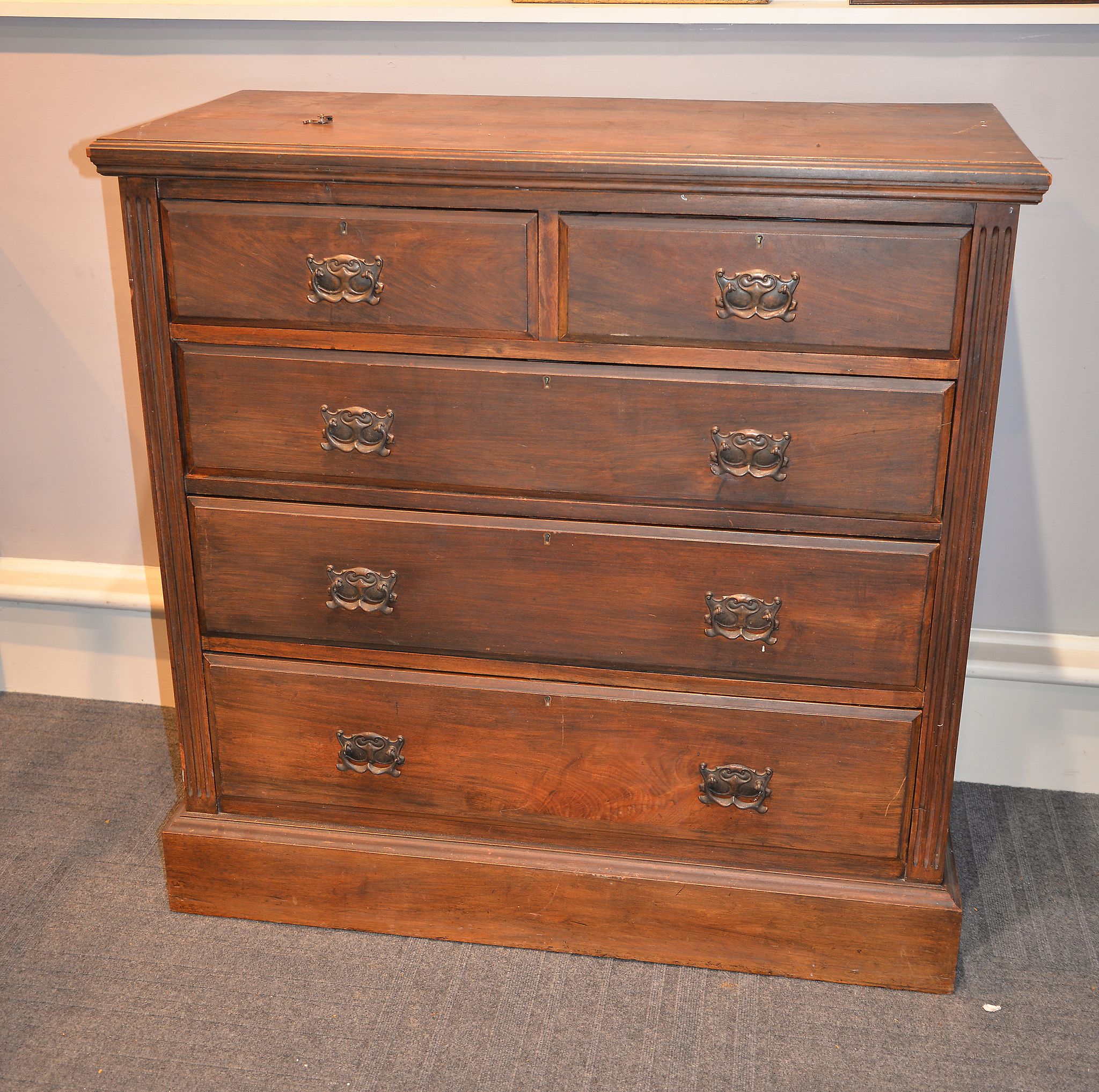 An Edwardian walnut chest of drawers, with two short and three long