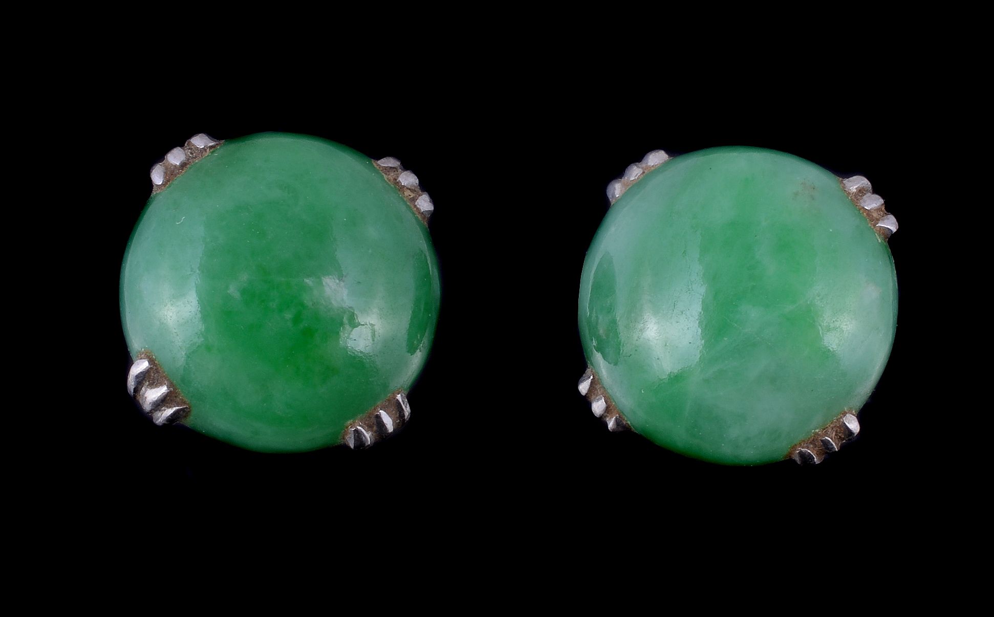 A pair of jadeite jade ear studs, the circular cabochon jadeite jade in four claw settings, with