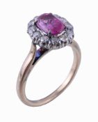 A pink sapphire and diamond ring, the oval cut pink sapphire claw set within a surround of