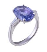 A sapphire and diamond ring, the central oval cut sapphire in a four claw setting between tapered