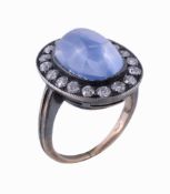 A sapphire and diamond ring, the oval cabochon sapphire within a surround of old brilliant cut