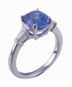 A sapphire and diamond ring, the oval cut sapphire in a four claw setting between tapered baguette