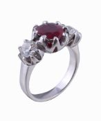 A ruby and diamond three stone ring, the oval cut ruby in a claw setting between two brilliant cut