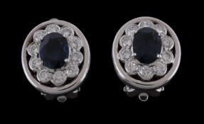 A pair of sapphire and diamond earrings, the central oval cut sapphire claw set within a surround