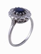 A sapphire and diamond cluster ring, the central oval cut sapphire claw set within a surround of