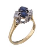 A sapphire and diamond ring, set with two oval cut sapphires claw set between brilliant cut