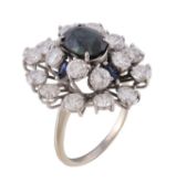 A sapphire and diamond ring, the central oval cut sapphire claw set within a surround of brilliant