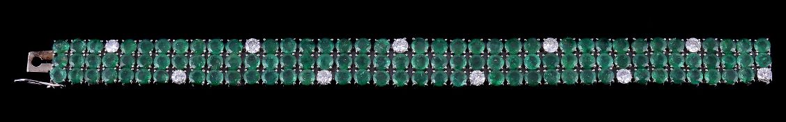An emerald and diamond bracelet, set with three rows of circular cut emeralds, with brilliant cut