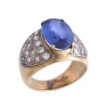 A sapphire and diamond ring, the oval cut sapphire in a four claw setting, between brilliant cut