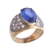 A sapphire and diamond ring, the oval cut sapphire in a four claw setting, between brilliant cut