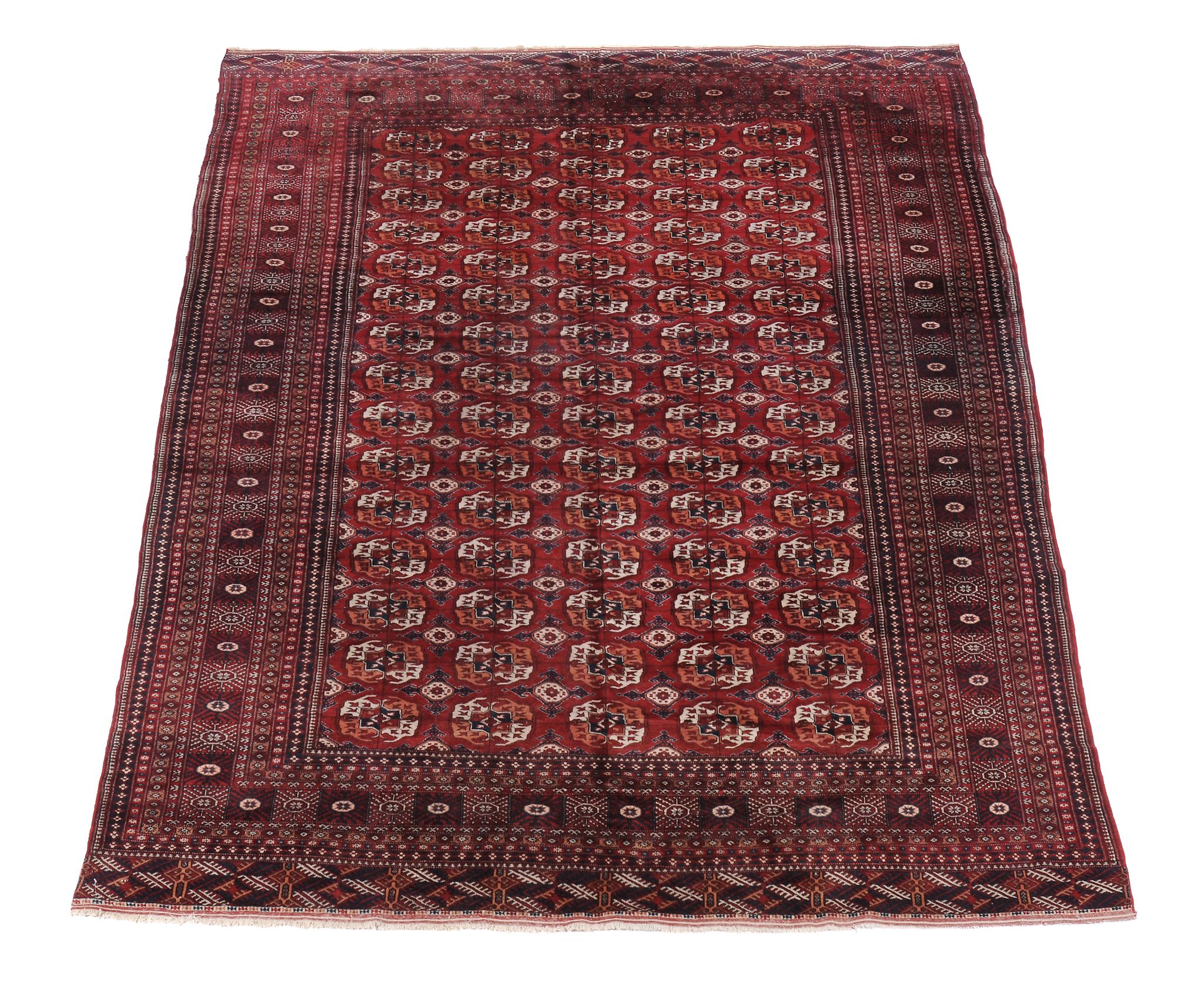 A Bokhara carpet, the madder field decorated with rows of geometric motifs and within multiple