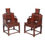 A pair of Chinese lacquered chairs, the seats each with exterior scene decoration, each 104cm high