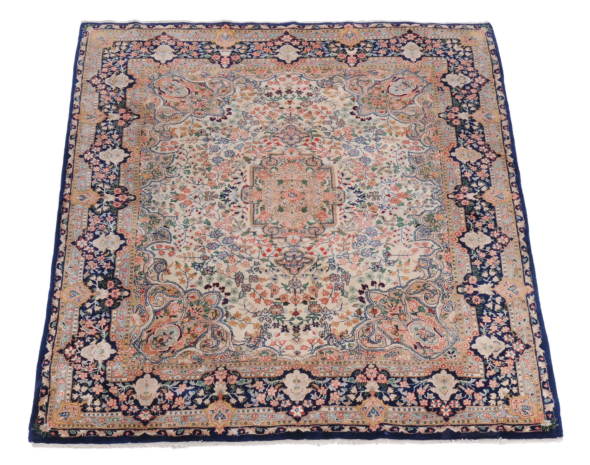 A Kirman carpet, the cream field decorated profusely with polycrome floral branches, within a navy