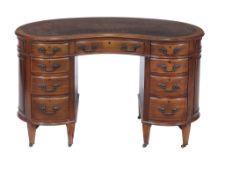 An Edwardian walnut kidney shaped desk, circa 1910, the leather inset top above an arrangement of