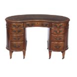 An Edwardian walnut kidney shaped desk, circa 1910, the leather inset top above an arrangement of