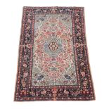 A Kashan rug, the cream and sky blue field decorated profusely with red and polychrome flowers,