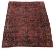 A Sarouk carpet, the madder field decorated with polycrome foliate motifs, within multiple borders,