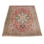 A Heriz carpet, the madder field with central navy and cream medallion, cornered by spandrels,