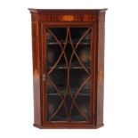 A George III mahogany and inlaid hanging corner cabinet, circa 1800, in the manner of Thomas