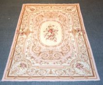 A modern rug in Aubusson style, woven in shades of pale pink, sepia, and cream, with central panel