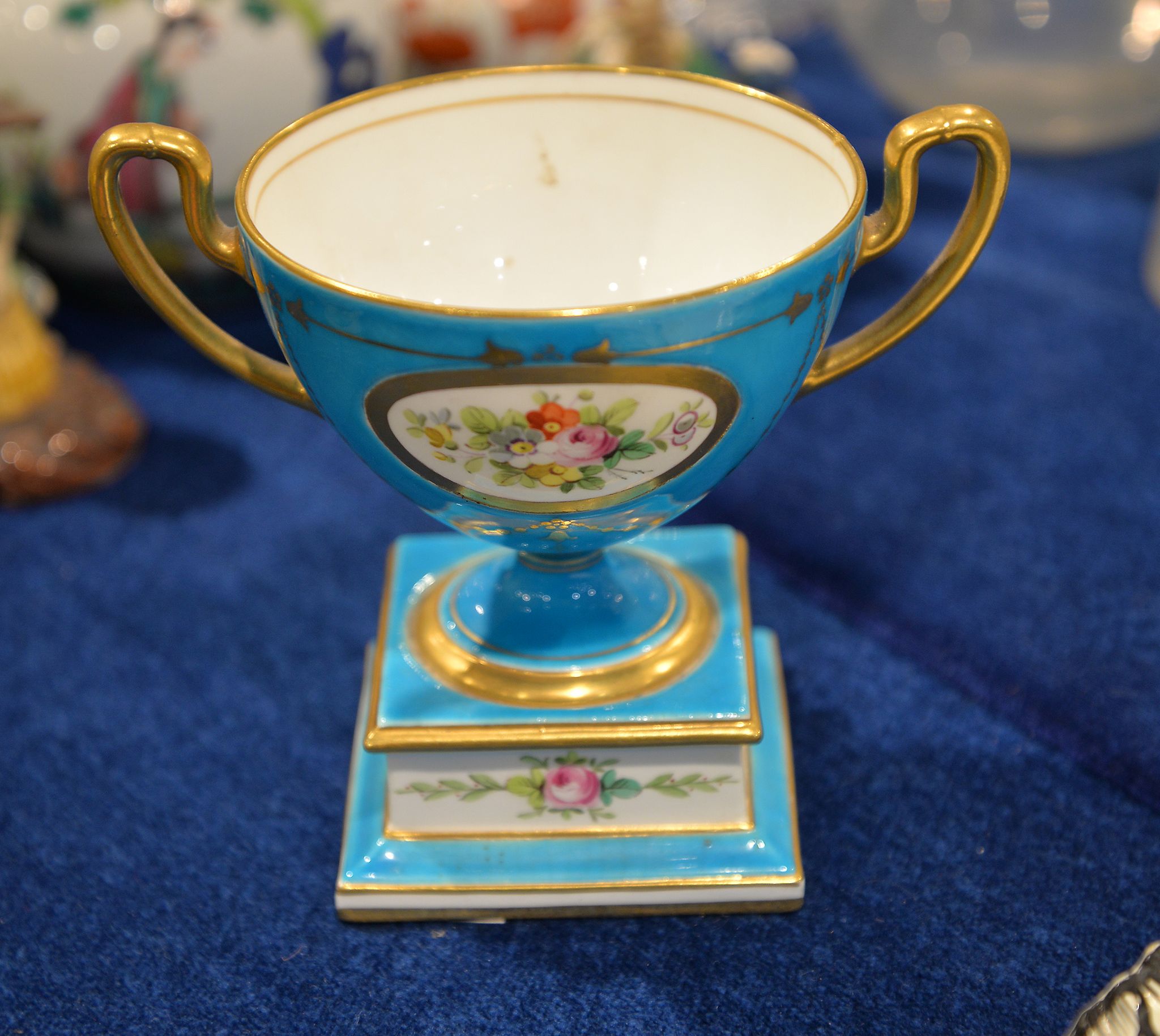 A Minton urn shaped two handled vase, painted with flowers, within gilt cartouches, on a turquoise