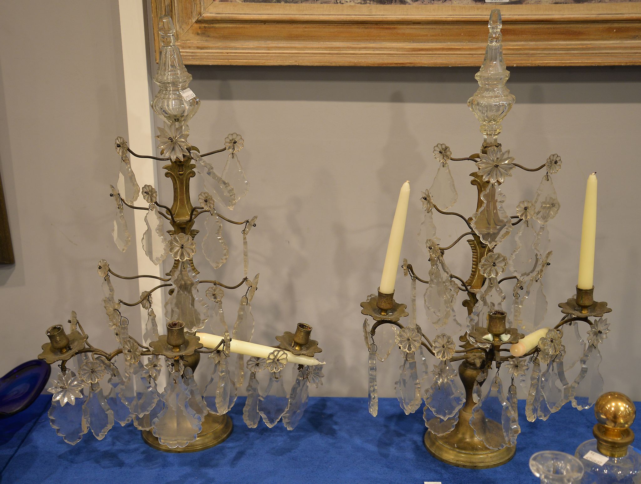 A pair of brass and glass three branch candelabra in Louis XV style, each arm suspending faceted