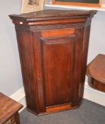A George III mahogany cupboard, with fretwork frieze above a fielded panel door enclosing fixed