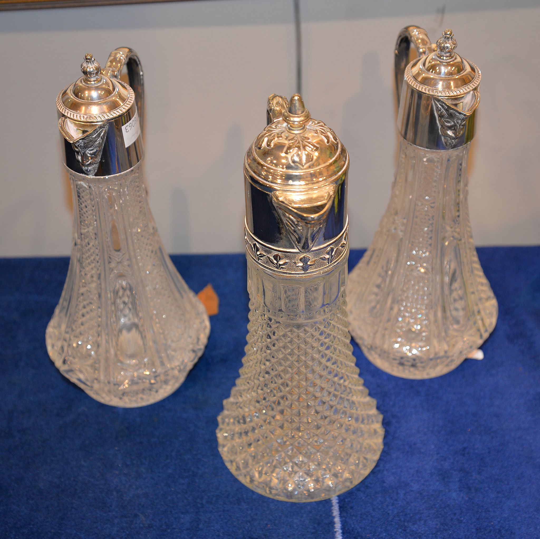 A press moulded glass and silver plate mounted claret jug, together with a pair of similar smaller