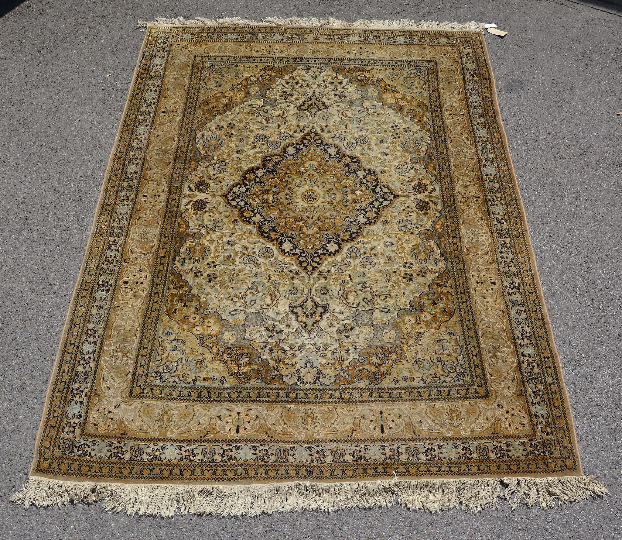 A woven carpet, of Kashan design, the pale field decorated with floral foliage and centred by a navy