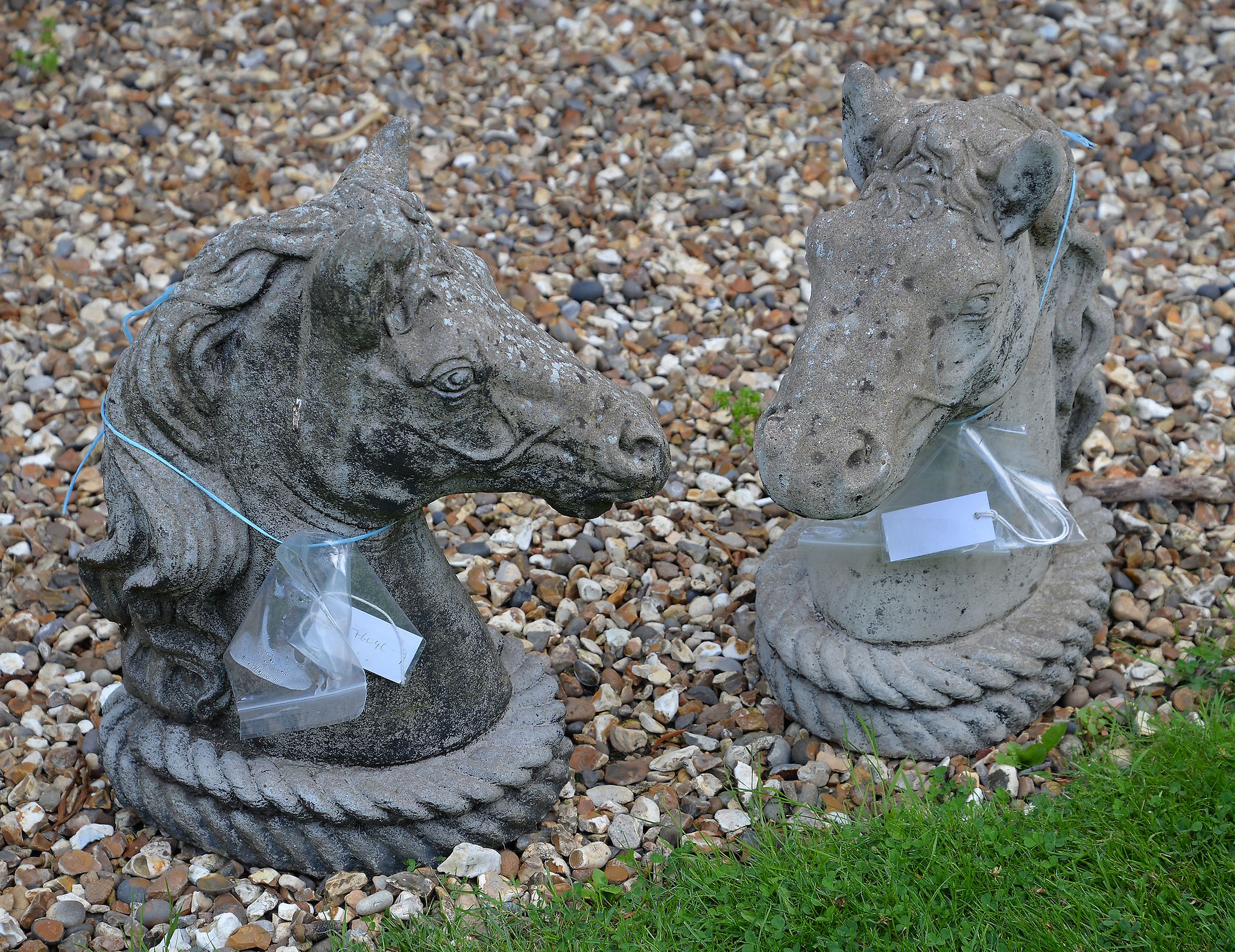 A pair of composition stone horse head pier finials, each 50cm high