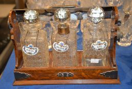 An oak and silver plate mounted three-bottle tantalus, various bottles, each with associated china