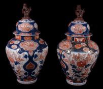 A pair of Imari style vases and covers, each of inverted baluster form rising to a cylindrical neck,