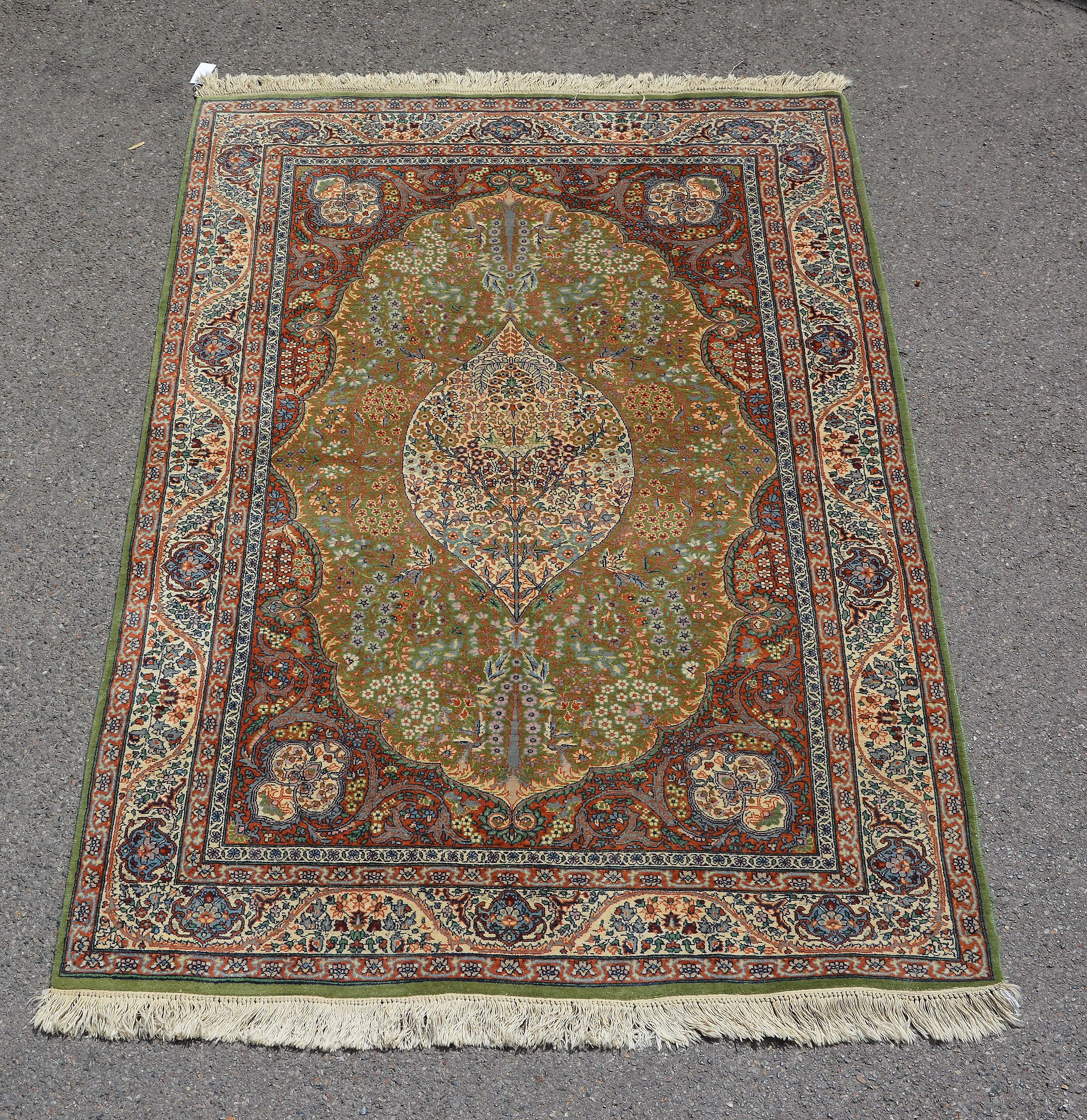 A woven rug, of Kashan design, the green field, medallion and spandrels decorated profusely with
