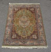 A woven rug, of Kashan design, the green field, medallion and spandrels decorated profusely with