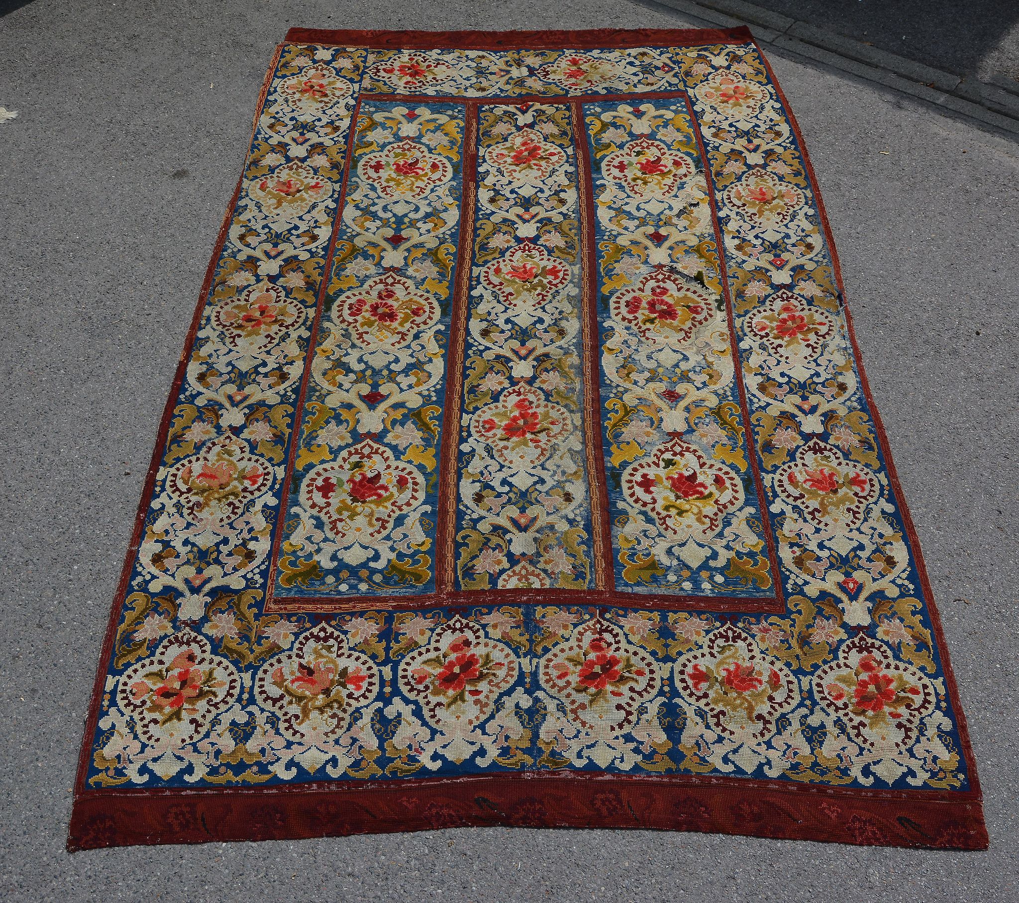 A Victorian needlepoint rug, the navy field decorated with repeated cartouche medallions decorated