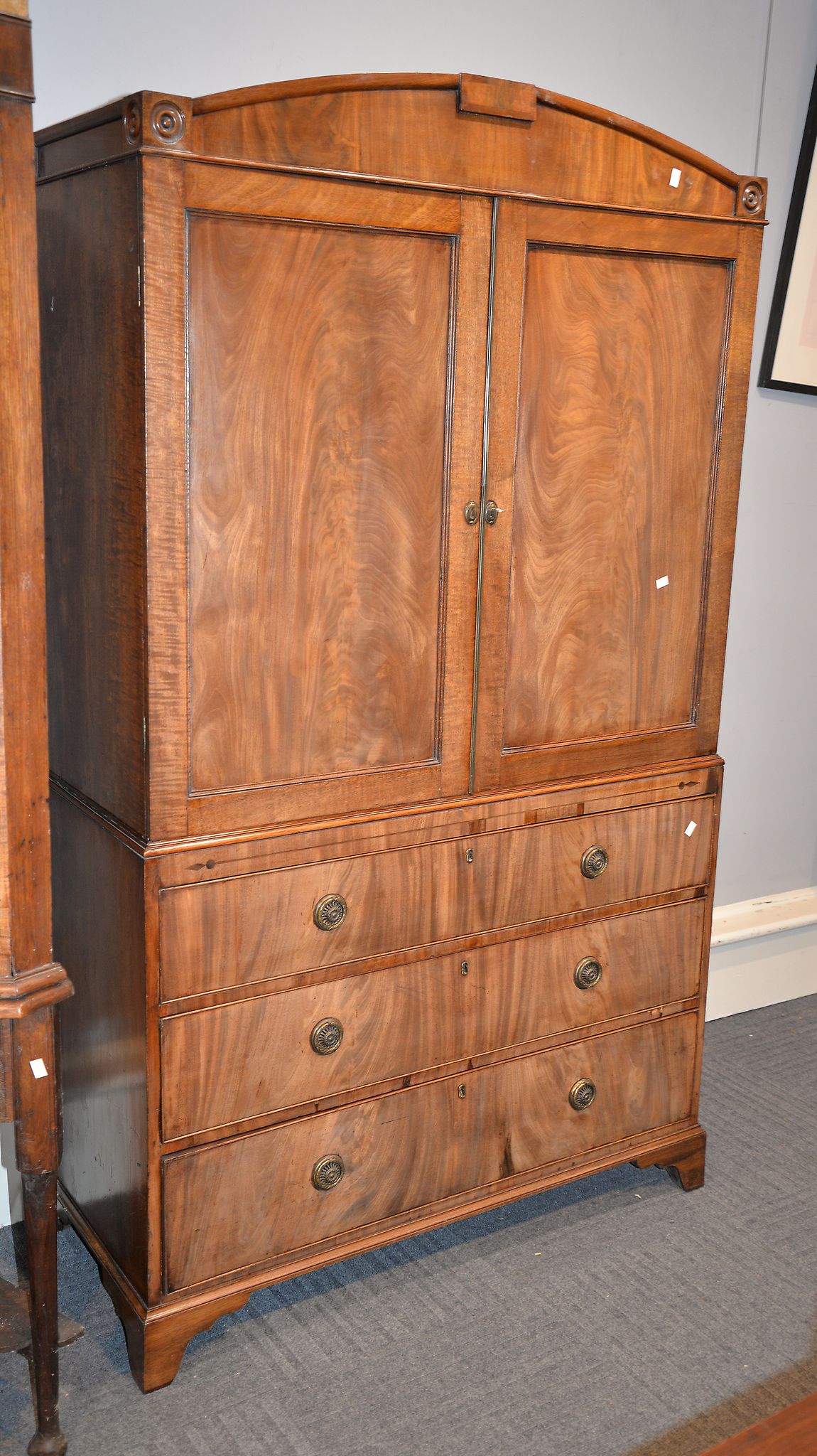 A Regency mahogany linen press with arched pediment and bullseye mouldings above a pair of doors