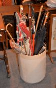 A collection of various walking sticks and umbrellas to include a Malacca example, with nielowork