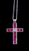 A ruby and diamond cross pendant, the French cut rubies in channel settings with a central step cut