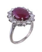 A ruby and diamond cluster ring, the oval cabochon ruby claw set within a surround of brilliant cut